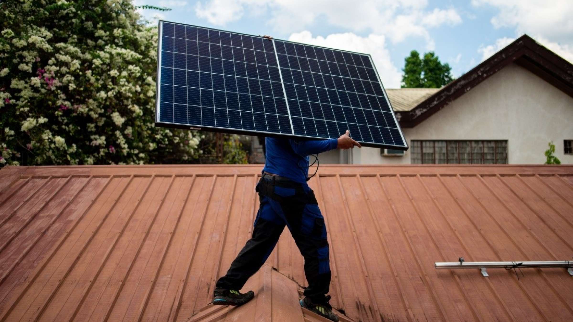 A worker from PHILERGY, a German-Filipino supplier and installer of solar energy, carries a solar panel during a home installation